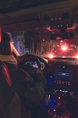 Şehirde geceleri modern arabasını süren genç bir kadın. Gece yolu, arabanın içi manzaralı..