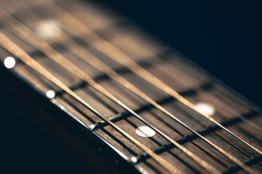 Akustik gitarın bir parçası, siyah arka planda gitar panosu. Gitar tellerini kapat, makro çekim.