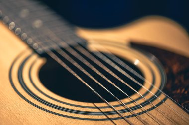 Gitar ve telleri sığ alan derinliğinde yakın çekim, yumuşak odaklanma. Profesyonel müzik enstrümanının ses deliği ve metal telleri.