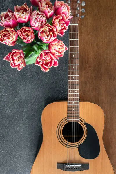 Akustik gitar, not defteri ve pembe bahar lale çiçekleri, üst manzara..