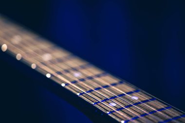 Kapat, akustik gitardaki dizgiler bulanık siyah arkaplan kopyalama alanı üzerinde.