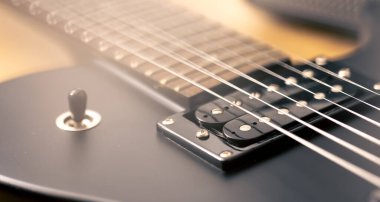 Elektro gitarın detaylarının fotoğrafı. Arka planda siyah elektro gitar, makro çekim.