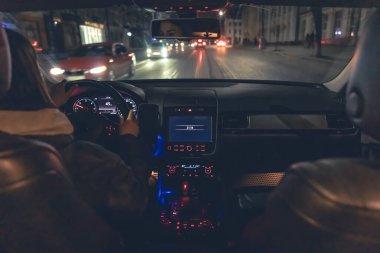 Şehirde geceleri modern arabasını süren genç bir kadın. Gece yolu, arabanın içi manzaralı..