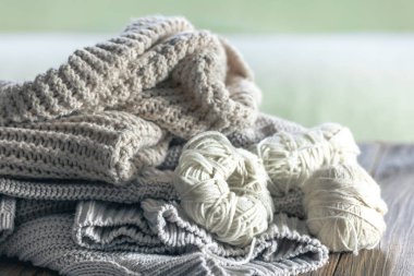 Ahşap arka planda örülmüş bir kazak yığını. Minimalizm, örülmüş doku, düzen, konfor, makro.