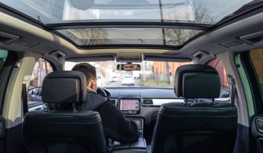 A male driver drives at speed through the streets of the city, a view from inside the car.