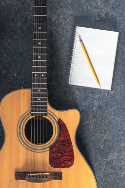 Siyah desenli arka planda akustik gitar ve defter, üst görünüm. Gitarla yakın plan müzik arkaplanı.