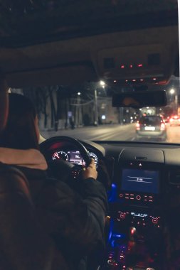 Şehirde geceleri modern arabasını süren genç bir kadın. Gece yolu, arabanın içi manzaralı..
