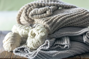 Ahşap arka planda örülmüş bir kazak yığını. Minimalizm, örülmüş doku, düzen, konfor, makro.