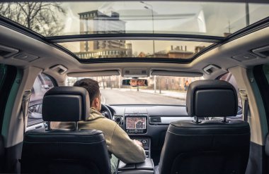 A male driver drives at speed through the streets of the city, a view from inside the car.