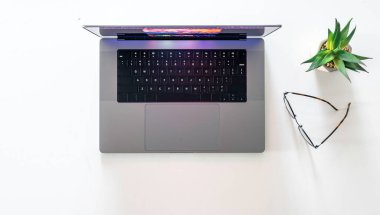 Modern bir dizüstü bilgisayar, gözlük ve saksı beyaz arka planda izole edilmiş..