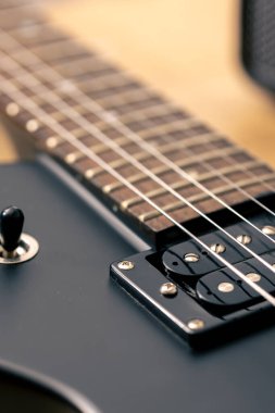 Elektro gitarın detaylarının fotoğrafı. Arka planda siyah elektro gitar, makro çekim.