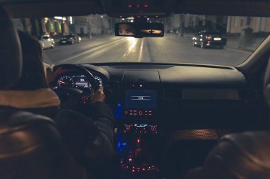 Şehirde geceleri modern arabasını süren genç bir kadın. Gece yolu, arabanın içi manzaralı..