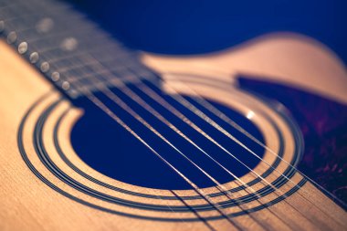 Gitar ve telleri sığ alan derinliğinde yakın çekim, yumuşak odaklanma. Profesyonel müzik enstrümanının ses deliği ve metal telleri.