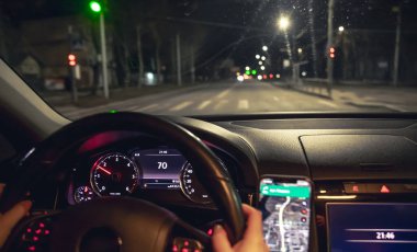 Sürücü elleri gece direksiyonda, gece direksiyonunda. Şehirde geceleri modern arabasını kullanan genç bir kadın. Navigator kullanıyor..