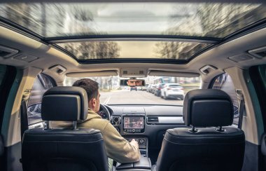 A male driver drives at speed through the streets of the city, a view from inside the car.