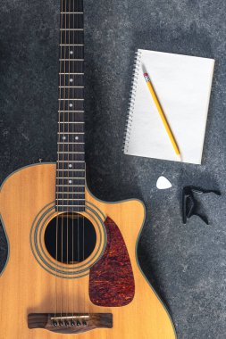Siyah desenli arka planda akustik gitar ve defter, üst görünüm. Gitarla yakın plan müzik arkaplanı.