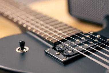 Elektro gitarın detaylarının fotoğrafı. Arka planda siyah elektro gitar, makro çekim.