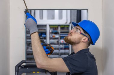 Mavi bir miğfer takan elektrikçi evin içindeki tavana elektrik kabloları yerleştiriyor..