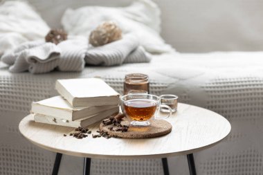 Odada bir fincan çay, kitaplar ve mumlarla ev kompozisyonu. Samimi bir ev geçmişi var. Boşluğu kopyala.