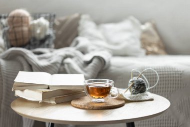 Bir fincan çay, bir mum ve örgü elementlerle sıcacık bir kompozisyon. Samimi bir ev geçmişi var. Boşluğu kopyala.