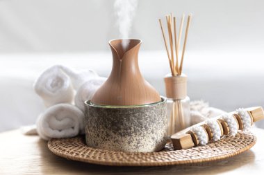 Temel yağ aroması yayıcı nemlendirici havadaki su maddelerini dağıtıyor. Aroma yağı yayıcı lamba bir masada. Aromaterapi ve sağlık hizmeti kavramı.