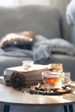 Odanın içindeki bir masanın üzerinde bir fincan çay ve kitaplar. Rahat ev kompozisyonu.