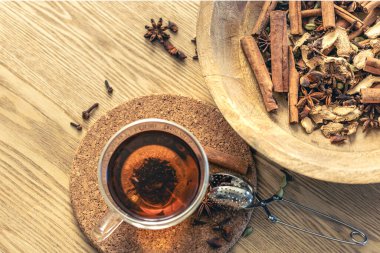 Bir fincan taze siyah çay, ahşap masada değişik baharatlar. Üst Manzara. Bir fincan çay, çay için baharat..