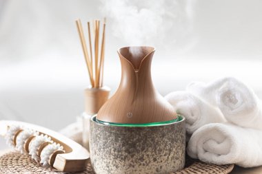 Temel yağ aroması yayıcı nemlendirici havadaki su maddelerini dağıtıyor. Aroma yağı yayıcı lamba bir masada. Aromaterapi ve sağlık hizmeti kavramı.