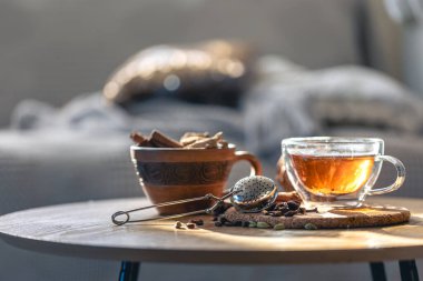 Çay seremonisi, bir bardak siyah çay ve bulanık arka planda çaydanlık. Ahşap bir masada tarçın kokulu sıcak çay..