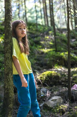 Plastikle kirletilmiş bir ormanda üzgün bir kız. Doğa kirliliği kavramı. Bir çocuk doğada çöp görür..