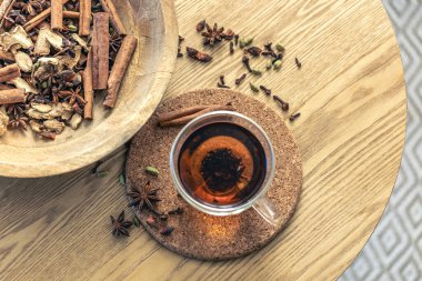 Bir fincan taze siyah çay, ahşap masada değişik baharatlar. Üst Manzara. Bir fincan çay, çay için baharat..