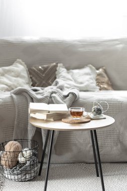 Bir fincan çay, bir mum ve örgü elementlerle sıcacık bir kompozisyon. Samimi bir ev geçmişi var. Boşluğu kopyala.