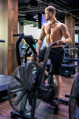 Bir hava bisikleti üzerinde tam yükseklikte egzersiz yapıyor. Spor salonundaki genç sporcu. Spor yaşam tarzı. Yüksek kalite fotoğraf