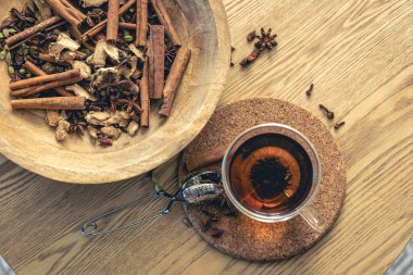 Bir fincan taze siyah çay, ahşap masada değişik baharatlar. Üst Manzara. Bir fincan çay, çay için baharat..