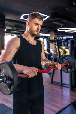 Spor salonunda kollarını halterle sallayan genç bir sporcu. Spor yaşam tarzı. - Evet. Yüksek kalite fotoğraf
