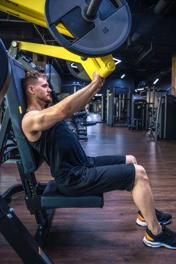 Spor salonundaki bir sporcu halterle trisepsi sallıyor. Spor yaşam tarzı. Spor hobileri ve sağlık. - Evet. Yüksek kalite fotoğraf