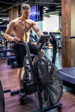 Bir hava bisikleti üzerinde tam yükseklikte egzersiz yapıyor. Spor salonundaki genç sporcu. Spor yaşam tarzı. Yüksek kalite fotoğraf