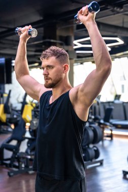 Genç atletik adam spor salonunda kollarını dambıllarla sallıyor. Spor yaşam tarzı. - Evet. Yüksek kalite fotoğraf