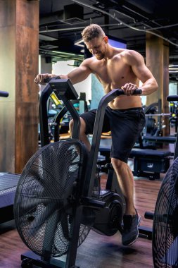 Bir hava bisikleti üzerinde tam yükseklikte egzersiz yapıyor. Spor salonundaki genç sporcu. Spor yaşam tarzı. Yüksek kalite fotoğraf