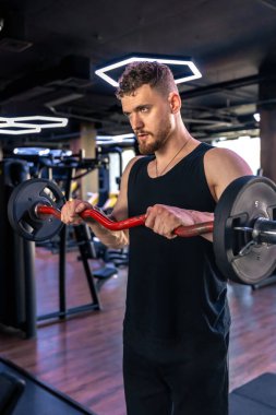 Spor salonunda kollarını halterle sallayan genç bir sporcu. Spor yaşam tarzı. - Evet. Yüksek kalite fotoğraf