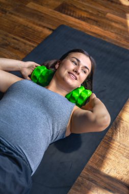 Hamile bir kadın, spor salonunda, bir paspasın üzerinde, masaj rulosuyla. Rahatlama ve masaj rulosuyla ısınma. Yüksek kalite fotoğraf. Üst görünüm