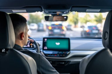 A male driver drives at speed through the streets of the city, a view from inside the car.