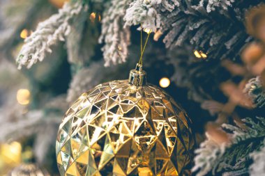 Yakın plan, desenli altın top bir Noel ağacına yakın çekim. Bulanık bir arka planda köknar dalında Noel oyuncağı.