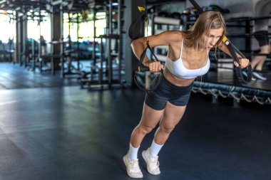 Kız spor salonunda TRX döngülerinde çalışıyor. Spor egzersizleri ve sağlıklı yaşam tarzı kavramı. Yüksek kalite fotoğraf