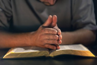 İncil okuyan bir adam. İncil 'e yakın çekimde erkek eli. Yüksek kalite fotoğraf. Din kavramı. Mesaj için yer var. Erkek eli İncil 'de.