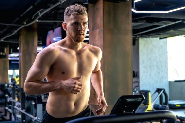 Spor salonunda koşu bandında bir sporcu. Spor salonundaki gömleksiz adam. Spor yaşam tarzı. Yüksek kalite fotoğraf