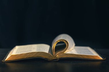 Siyah arka planda İncil 'i aç. Din kavramı. Yüksek kalite fotoğraf. Altın sayfalı İncil. Mesaj için yer var. İncil kitabına yakın çekim.