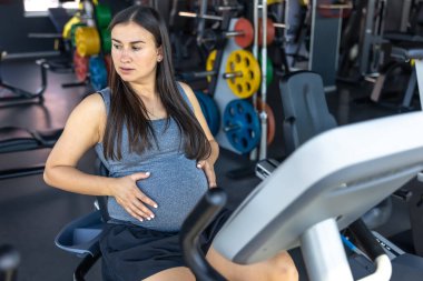 Spor salonundaki egzersiz makinesinde hamile bir kadın. Sağlıklı spor yaşam tarzı. Yüksek kalite fotoğraf