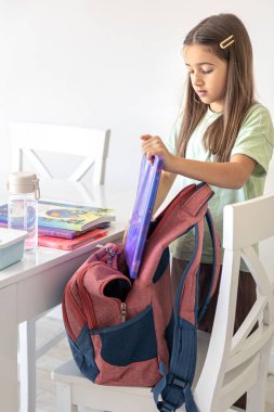 Kız, okula gidiyor. Sırt çantalı kız öğrenci. Yüksek kalite fotoğraf. Liseli bir kız ders için sırt çantasını topluyor. Tatlı bir kız sırt çantasına yemek koyar..