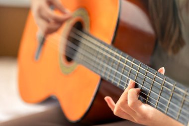 Kız gitar çalıyor. Gitar yakın plan. Yüksek kalite fotoğraf. Eller tellerin üzerinde, yakın plan. Klasik ya da akustik gitar.